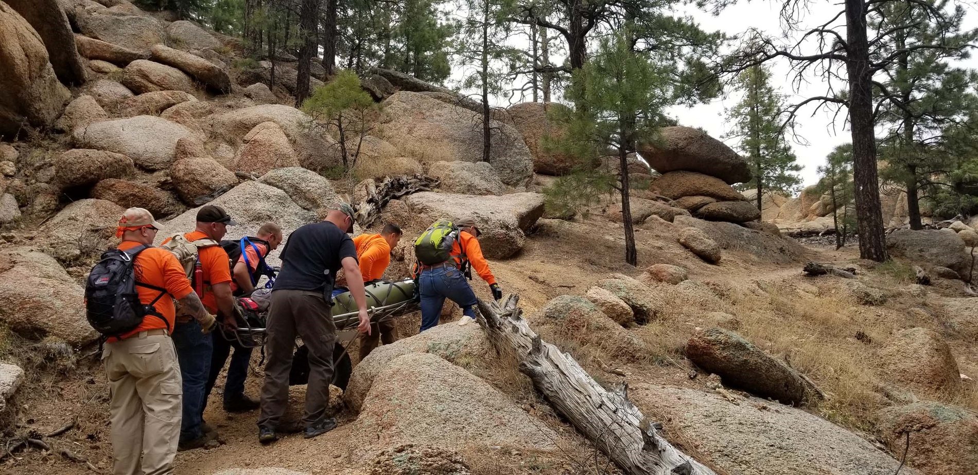 Arizona sheriffs' search and rescue volunteers carrying a patient litter over rocky terrain